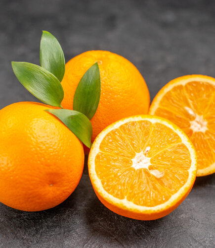 Close up view of set of yellow whole and chopped lemons on dark background